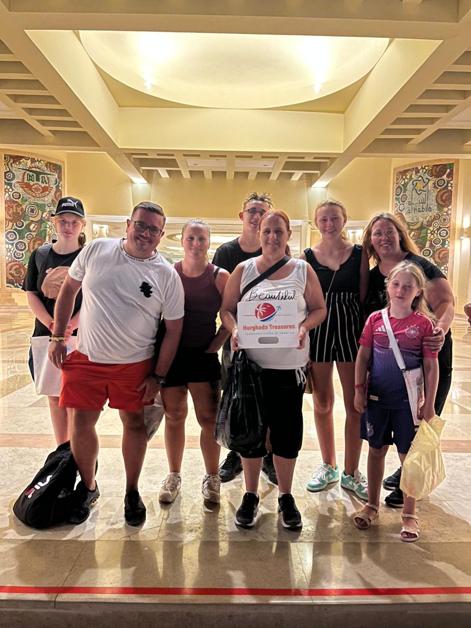 Large family group in the Siva Golden Bay hotel lobby with the Hurghada Treasures sign