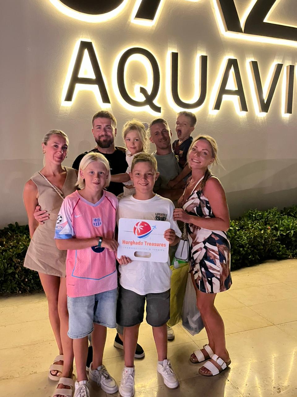 Families holding the Hurghada Treasures sign at Jaz Aquaviva resort entrance