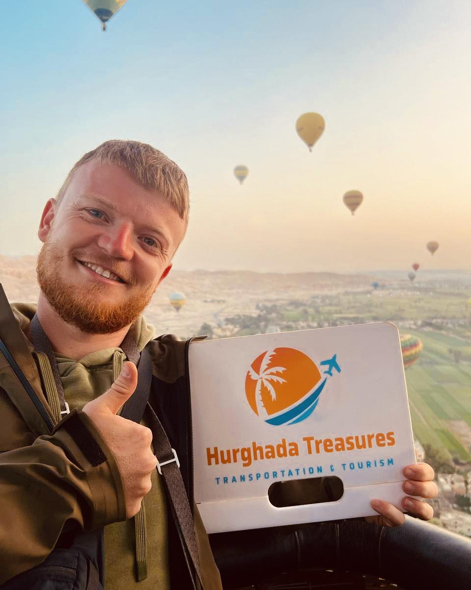 Guest in a hot air balloon over Luxor holding the Hurghada Treasures sign
